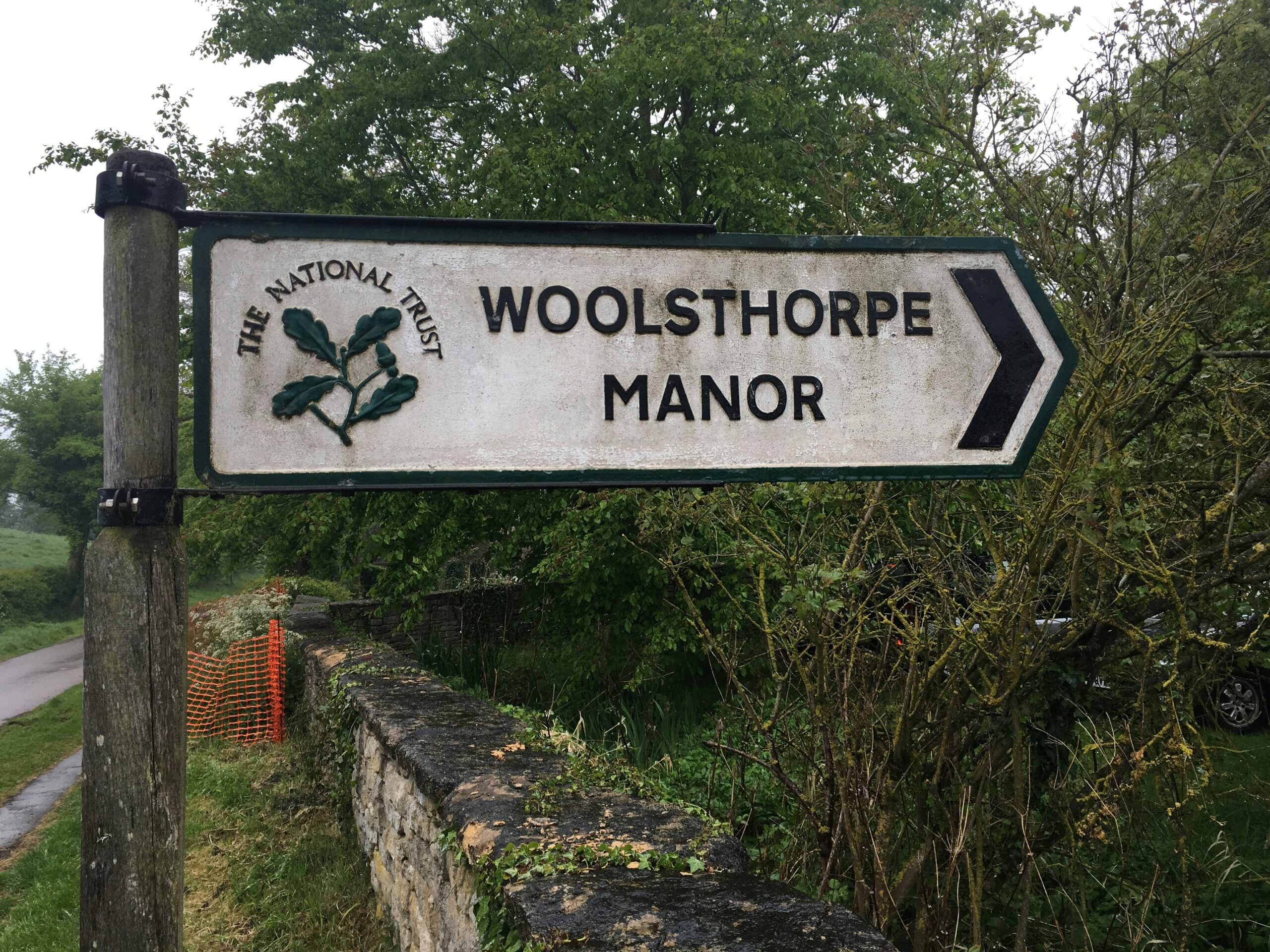 Sign for Woolsthorpe Manor, indicating the historic home of Sir Isaac Newton, surrounded by a picturesque setting that reflects the estate's heritage and natural beauty.